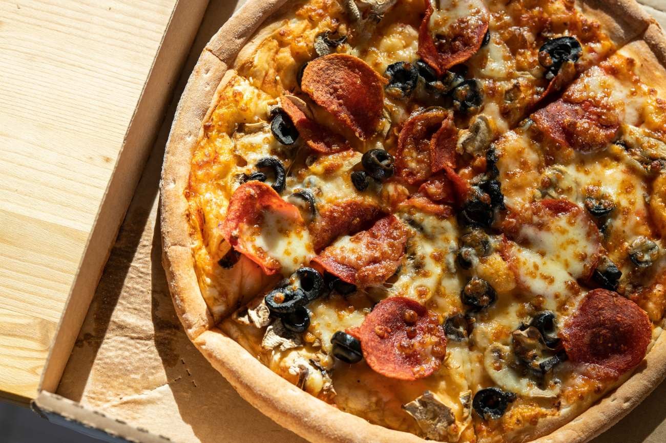 Pizza con salame piccante, funghi e olive nere